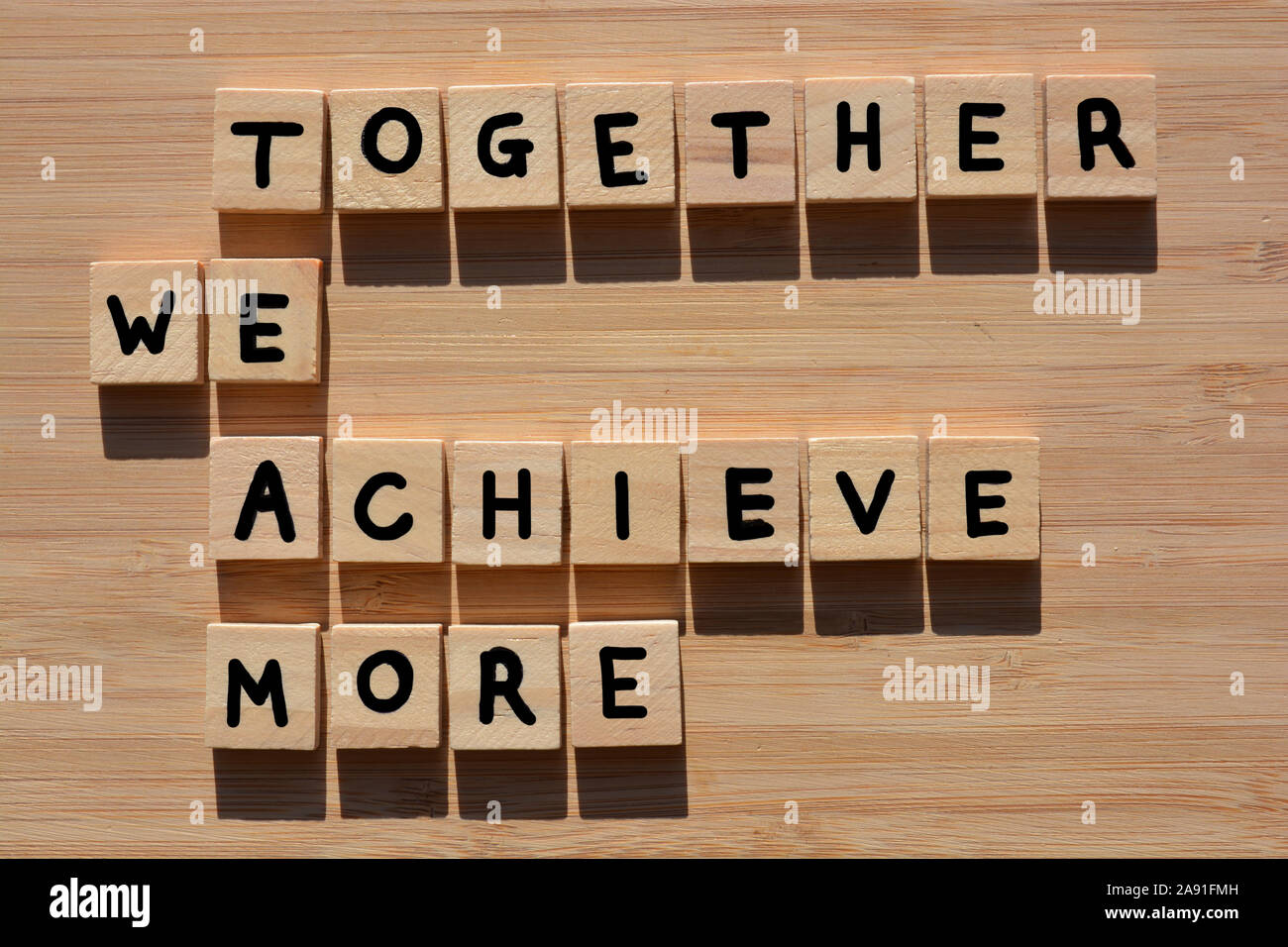 Zusammen erreichen wir mehr und das Wort Team in 3D Holz- Alphabet Buchstaben auf einem Bambus Holz Hintergrund Stockfoto