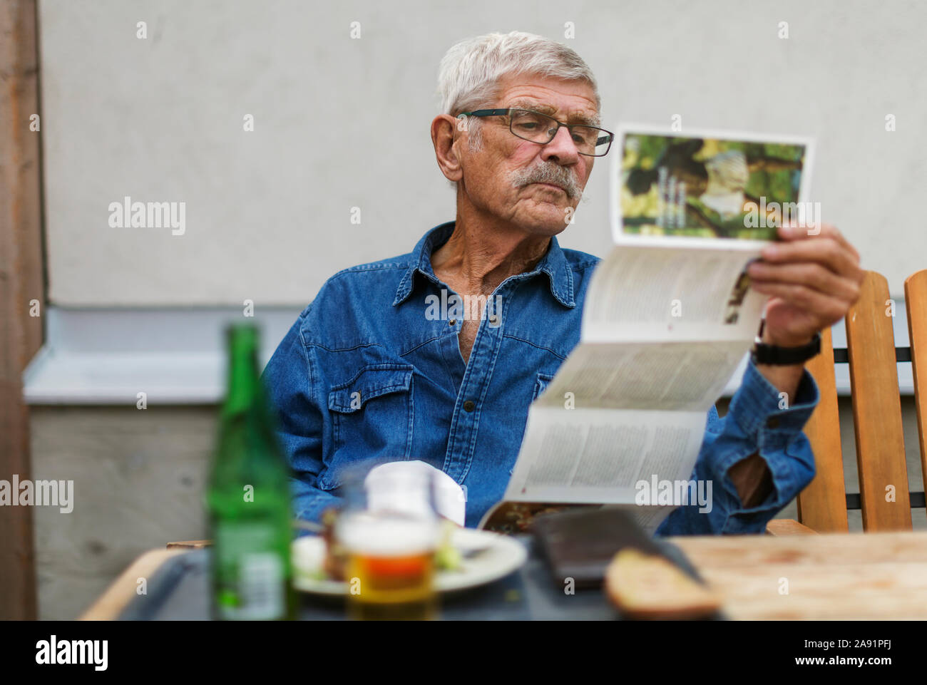 Älterer Mann draußen sitzen Stockfoto