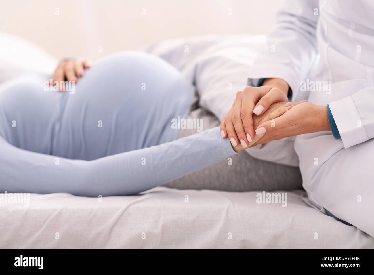 Nicht erkennbare Arzt Holding schwangere Frau Hand Innen Stockfoto