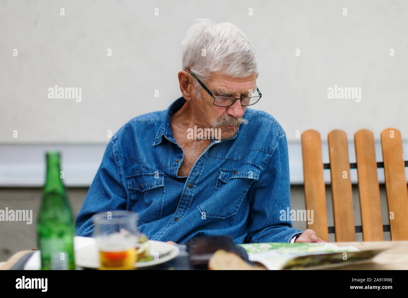 Älterer Mann draußen sitzen Stockfoto