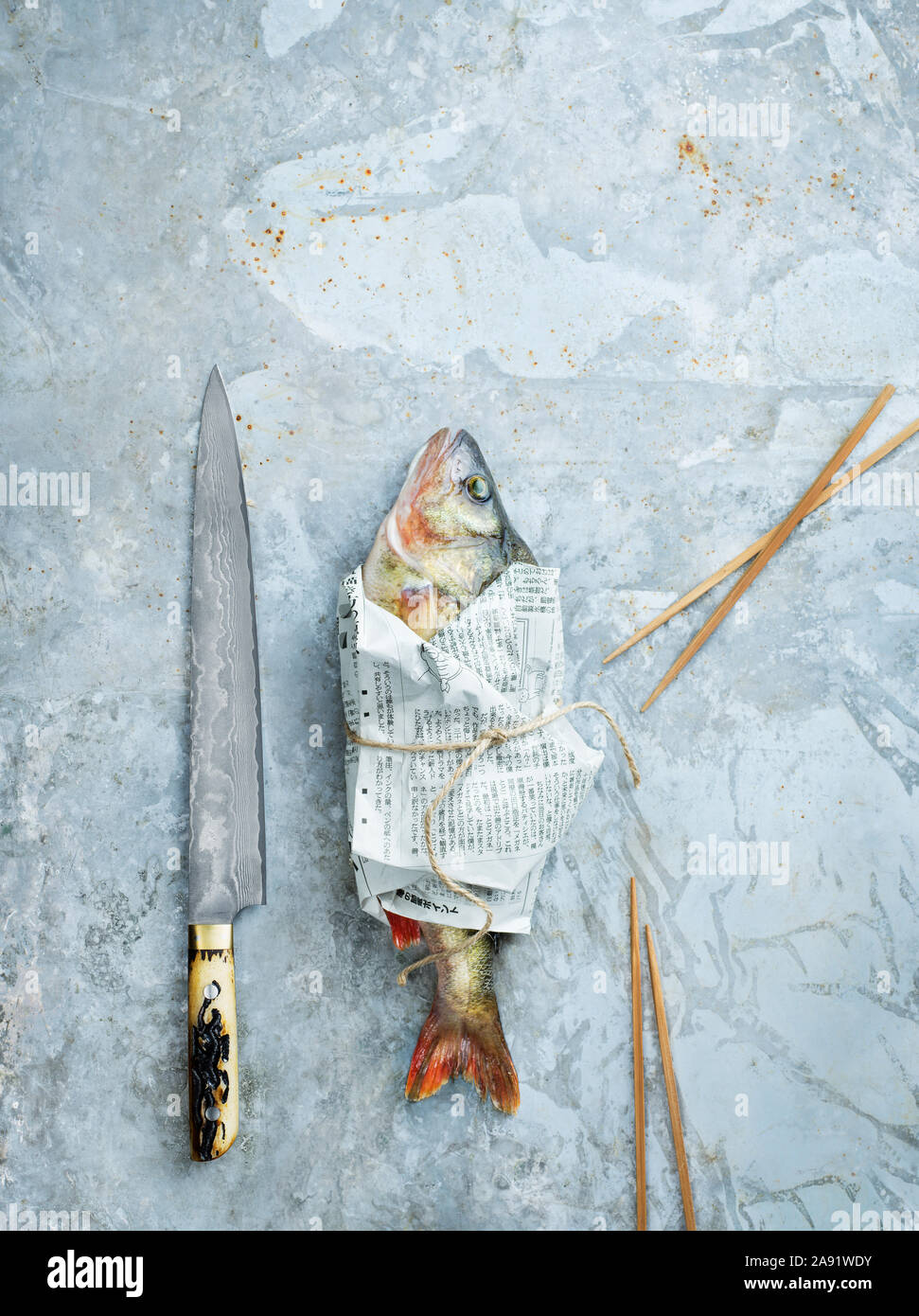 Messer und rohen Fisch in Zeitungspapier gewickelt Stockfoto