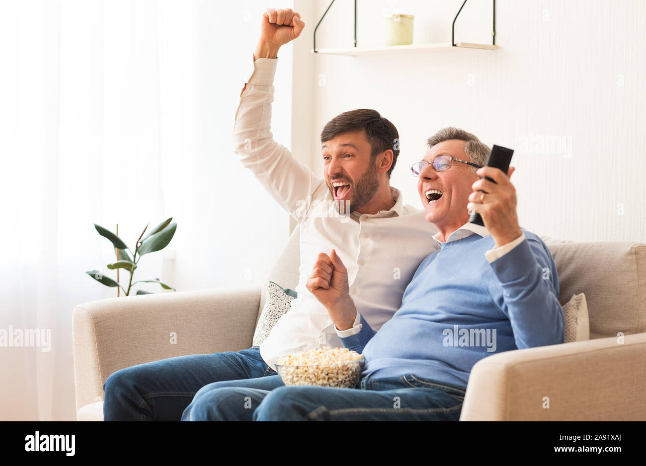 Ältere Vater und Sohn Middle-Aged Sport beobachten Auf TV Indoor Stockfoto
