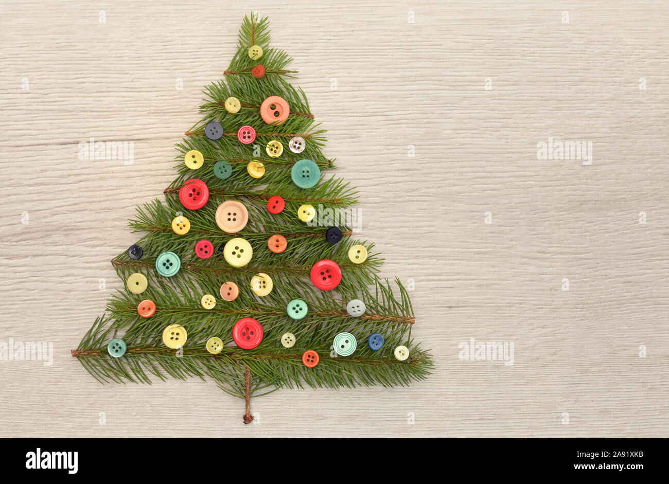 Weihnachtsbaum mit Kiefernzweigen und Tasten auf hölzernen Tisch Stockfoto