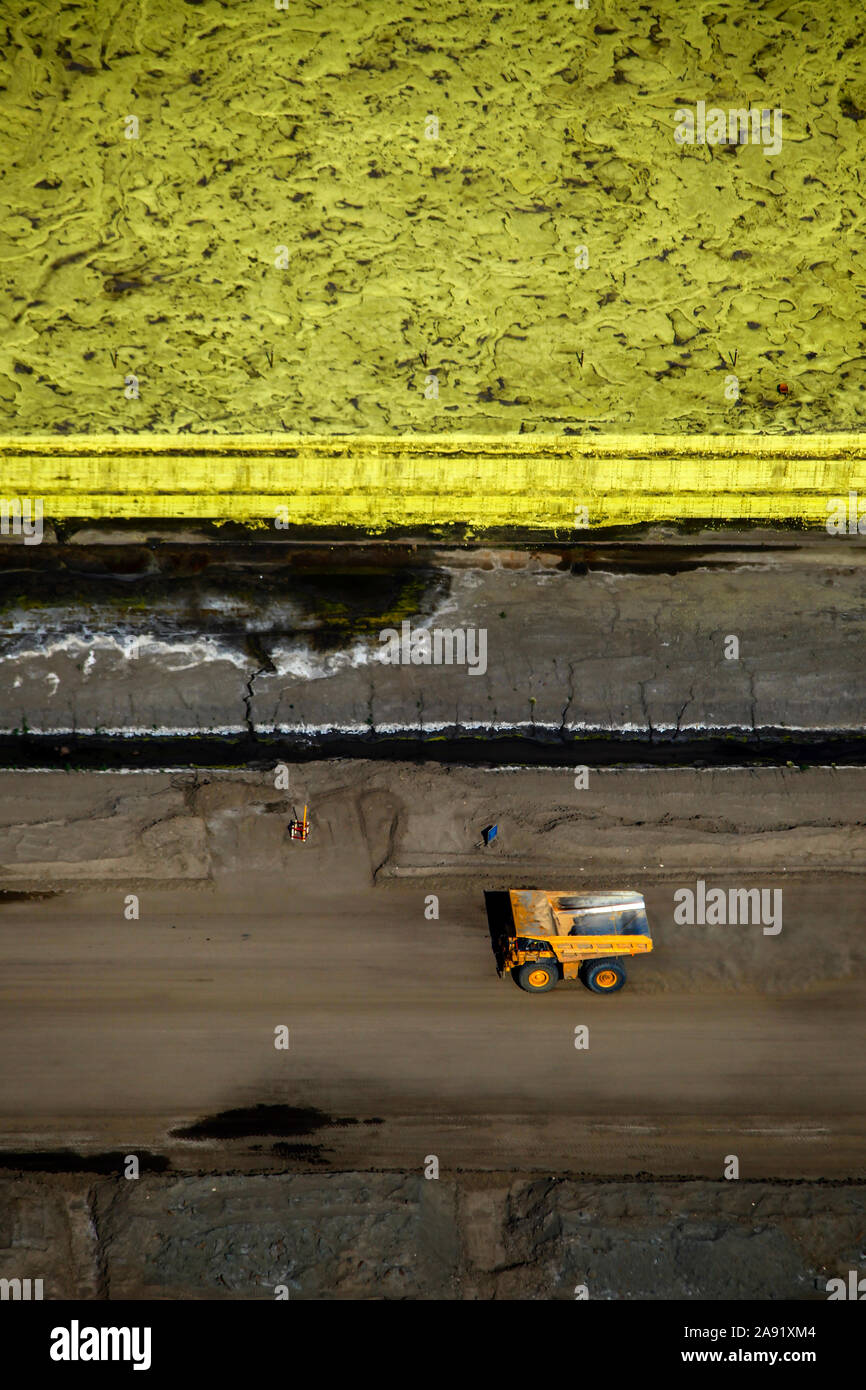 Ein Dump Truck Rennen durch einen Berg von Schwefel bei einem der Öl sand Gruben in Fort McMurray in Alberta, Kanada. Der Schwefel ist ein Nebenprodukt aus der Raffination von Bitumen und stellt ein großes Problem für sich. Ab 2006 gab es 15 Millionen Tonnen Schwefel an der Abbaustätten eingelagert sind und der Preis für die Aufrechterhaltung der giftigen Abfluß kräftigen. Die Athabasca Oil Sands Kaution gehört zu den größten in der Welt. Die Bitumen, auch allgemein namens tar (tar sands), enthält viele Kohlenwasserstoffe, sondern ist notorisch schwer zu extrahieren. Auf 100 BTU von Energie gewonnen, 70 BTU ist verloren Stockfoto