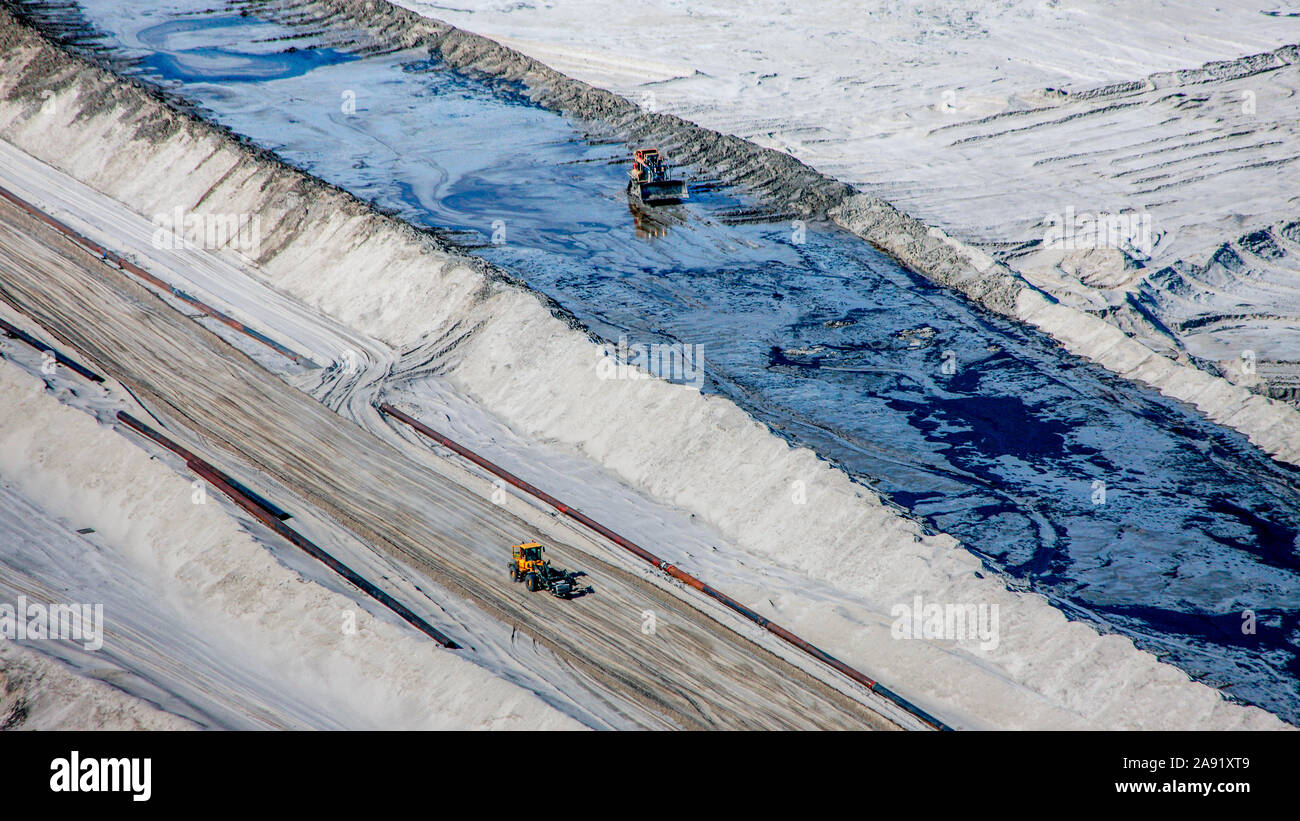 Bulldozer verbreiten sich die toxischen Abfälle in einer der enormen Bergeteiche in Fort McMurray in Alberta, Kanada. Die Teiche sind unter der größte Mann, Strukturen in der Welt, die mehr als 175 Quadratkilometern. Sie stellen eine zusätzliche Herausforderung an die Oil Sands Produktion: auch nach Ende der Produktion, kann es bis zu 30 Jahre für den Schlick, die in den Teichen bis zu trocknen. Das kontaminierte Wasser ist giftig für alle Lebewesen. Die Athabasca Oil Sands Kaution gehört zu den größten in der Welt. Die Bitumen, auch allgemein namens tar (tar sands), enthält viele Kohlenwasserstoffe, aber notori ist Stockfoto
