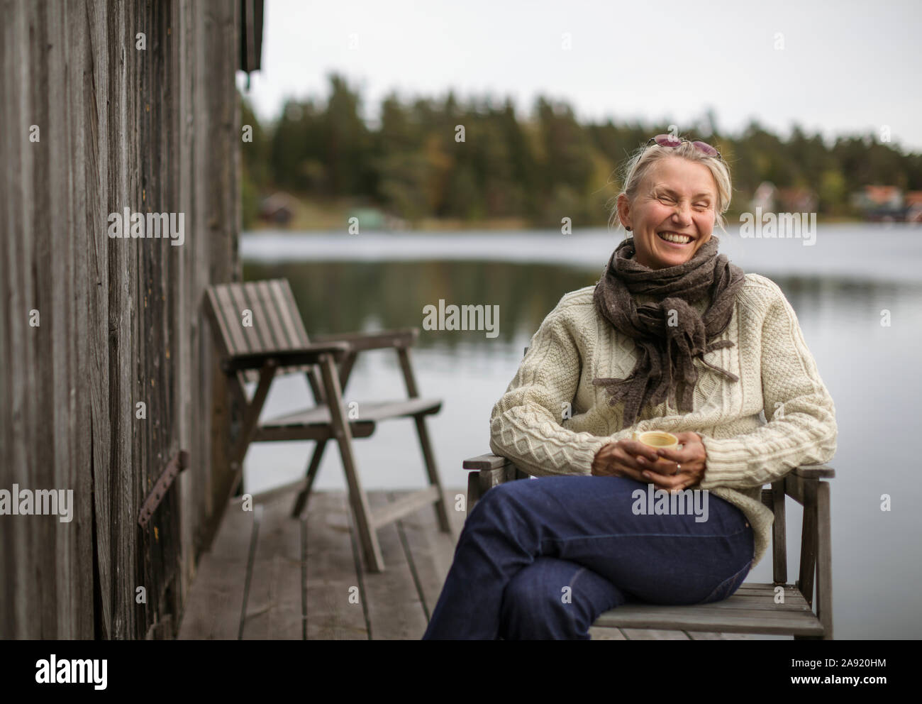Lächelnde Frau sitzt am See Stockfoto