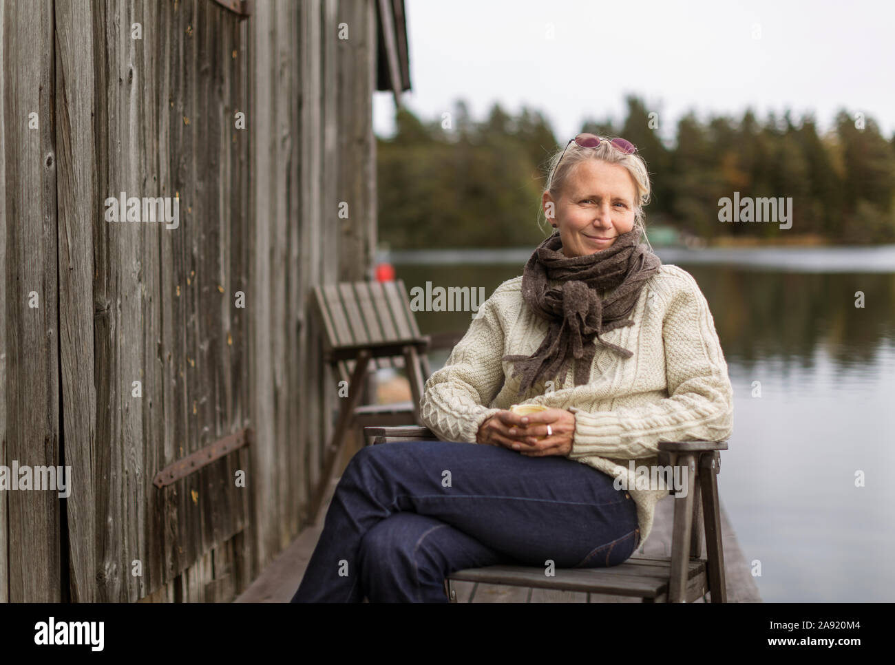 Lächelnde Frau sitzt am See Stockfoto