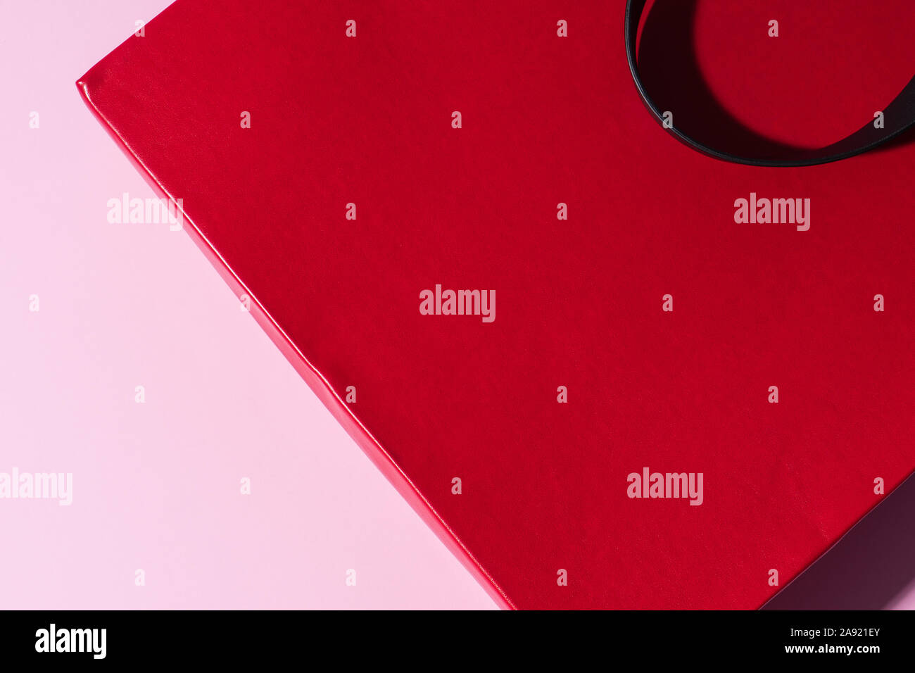 Rot Leder Tasche mit schwarzem Griff auf der rosa Hintergrund. Platz für Logo oder Werbung. Paket für Shopping. Stockfoto