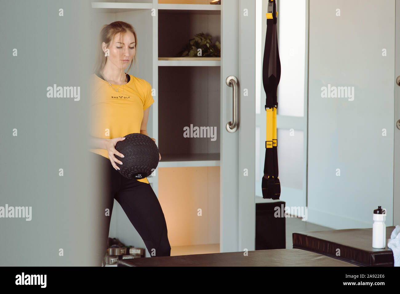 Fitness cross-Fit girl Holding med Kugel für Training in einem Fitness-studio. Junge kaukasier Athlet Mädchen tun Ausdehnung mit gewichteten Ball. Stockfoto