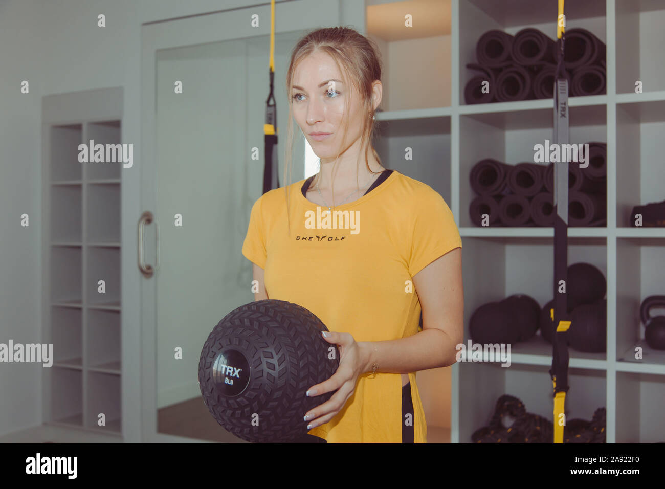 Fitness cross-Fit girl Holding med Kugel für Training in einem Fitness-studio. Junge kaukasier Athlet Mädchen tun Ausdehnung mit gewichteten Ball. Stockfoto