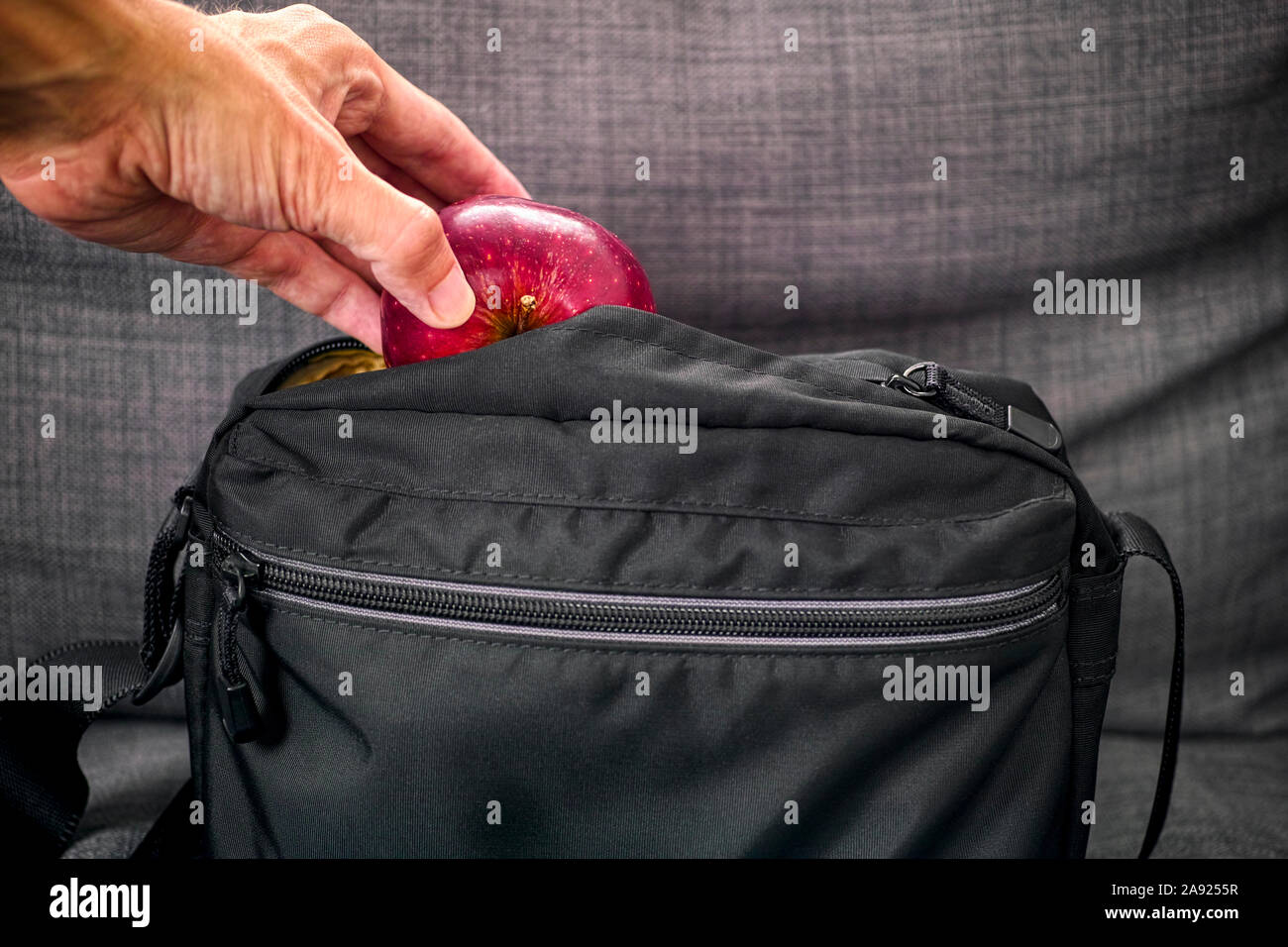 Person Hand roten Apfel in der schwarzen Tasche. Close Up. Stockfoto