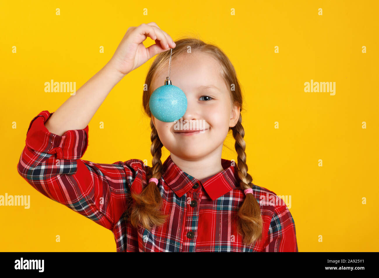 Glückliche kleine Mädchen mit christmas Ball Spielzeug. Kind close-up auf einem gelben Hintergrund. Stockfoto