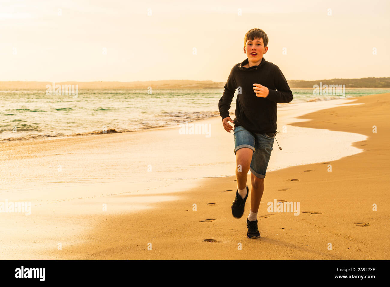 Junge läuft am Strand bei Sonnenuntergang Stockfoto