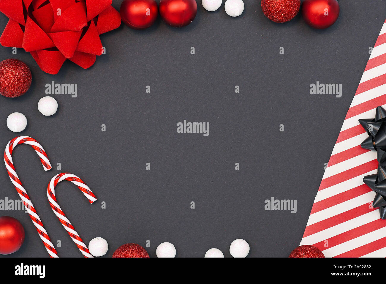 Elegante saisonale flach Hintergrund mit gestreiftem Geschenkpapier, Zuckerstangen, weißer Schnee Kugeln, red ribbon und Christbaumschmuck Kugeln o Stockfoto