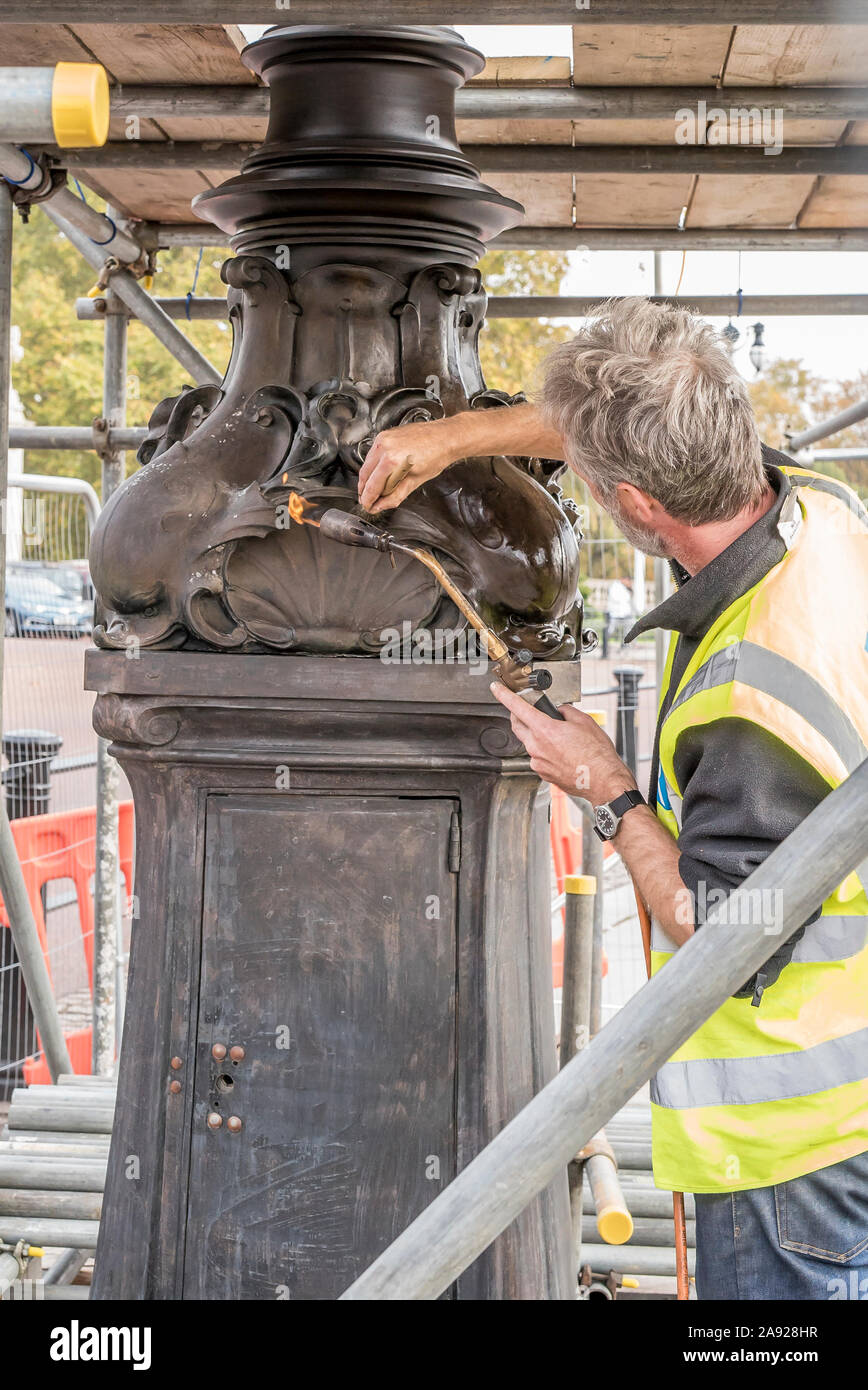 London, Großbritannien. 6. November 2019. Wesentliche Arbeit im Naturschutz findet an der Queen Victoria Memorial direkt vor dem Buckingham Palace entfernt. Spezialisierte Teams arbeiten mit einem bestimmten Gefühl der Dringlichkeit und einen akuten Bewusstsein der königlichen Frist gewährleistet die vollständige Entfernung/Demontage der unansehnlichen Gerüst vor der jährlichen Erinnerung Sonntag Parade am 10. November dieses Jahres gehalten werden. Eine isolierte Erhaltung Experte arbeiten alleine mit einem Brenner, blowlamp in der einen Hand und Pinsel für Wachs in die andere. Quelle: Lee Hudson Stockfoto