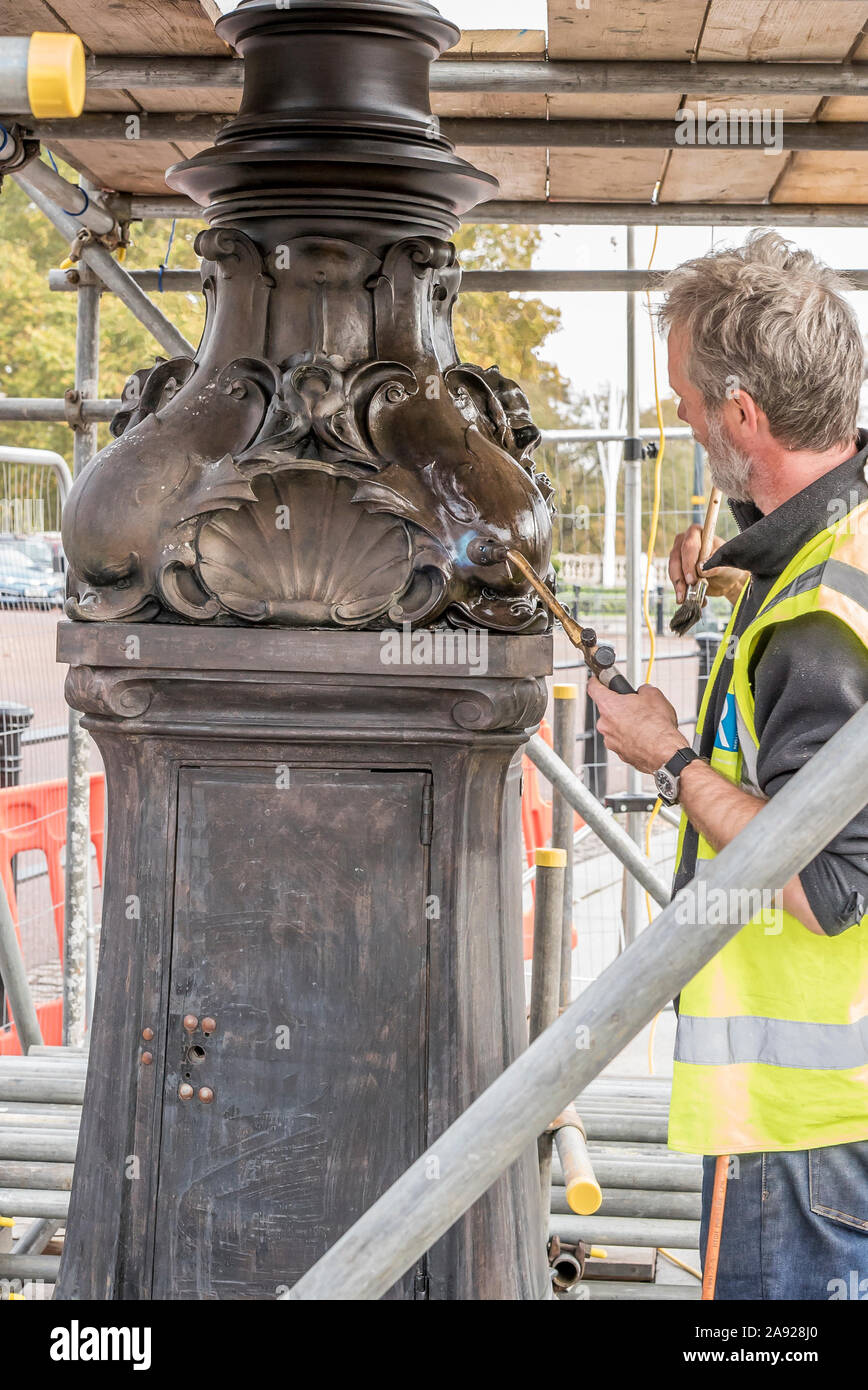 London, Großbritannien. 6. November 2019. Wesentliche Arbeit im Naturschutz findet an der Queen Victoria Memorial direkt vor dem Buckingham Palace entfernt. Spezialisierte Teams arbeiten mit einem bestimmten Gefühl der Dringlichkeit und einen akuten Bewusstsein der königlichen Frist gewährleistet die vollständige Entfernung/Demontage der unansehnlichen Gerüst vor der jährlichen Erinnerung Sonntag Parade am 10. November dieses Jahres gehalten werden. Eine isolierte Erhaltung Experte arbeiten alleine mit einem Brenner, blowlamp in der einen Hand und Pinsel für Wachs in die andere. Quelle: Lee Hudson Stockfoto