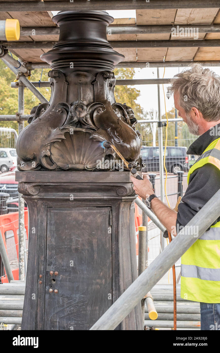 London, Großbritannien. 6. November 2019. Wesentliche Arbeit im Naturschutz findet an der Queen Victoria Memorial direkt vor dem Buckingham Palace entfernt. Spezialisierte Teams arbeiten mit einem bestimmten Gefühl der Dringlichkeit und einen akuten Bewusstsein der königlichen Frist gewährleistet die vollständige Entfernung/Demontage der unansehnlichen Gerüst vor der jährlichen Erinnerung Sonntag Parade am 10. November dieses Jahres gehalten werden. Eine isolierte Erhaltung Experte arbeiten alleine mit einem Brenner, blowlamp in der einen Hand und Pinsel für Wachs in die andere. Quelle: Lee Hudson Stockfoto