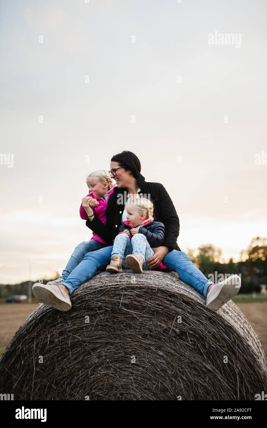 Mutter mit Töchtern sitzen auf dem Ballen Heu Stockfoto
