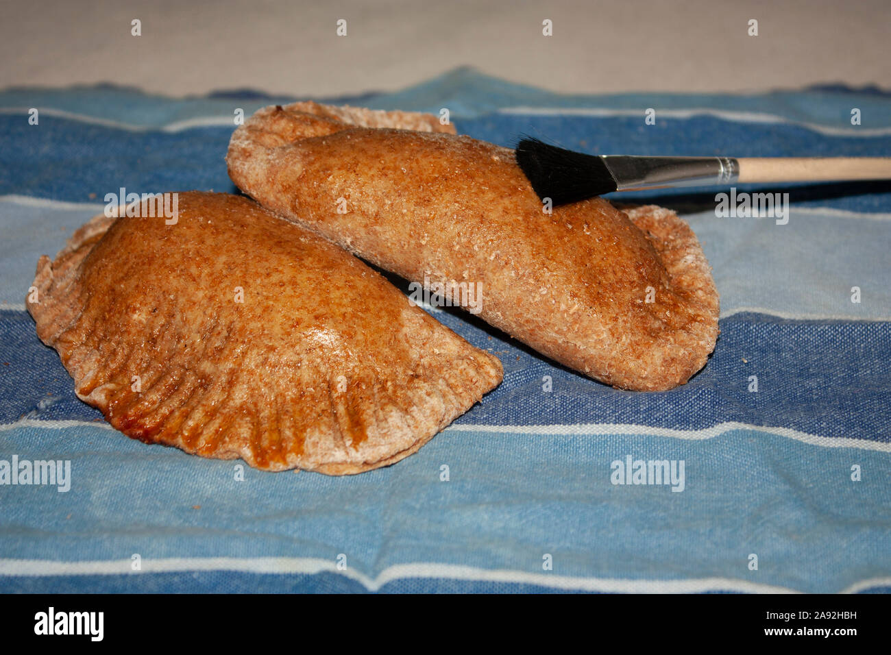Lackierung Pinsel einen goldenen Note an die frische, gesunde ganze gesalzen - Korn Bratlinge zu geben, gefüllt mit Knoblauch und Petersilie gewürzte Huhn Stockfoto