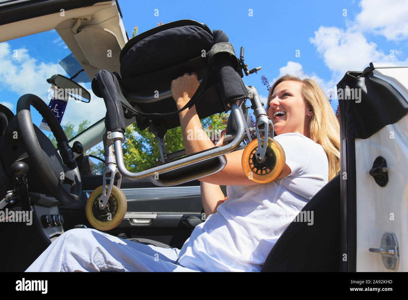 Frau mit Verletzungen des Rückenmarks ziehen Stuhl vom Rollstuhl in ihrem adaptiven Fahrzeug Stockfoto