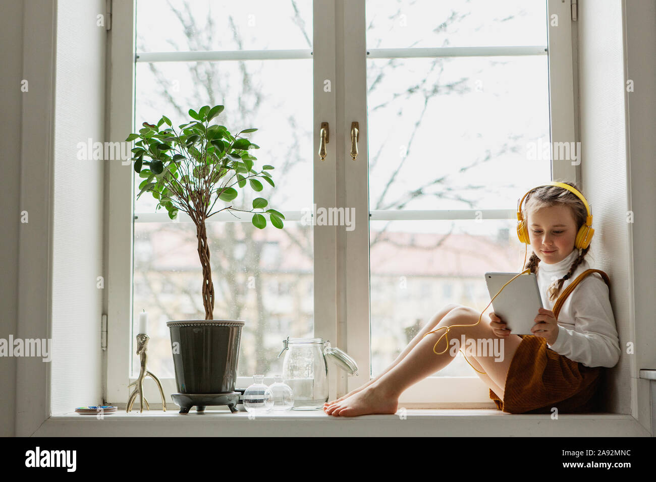 Mädchen sitzen auf Fensterbank mit digitalen Tablet Stockfoto