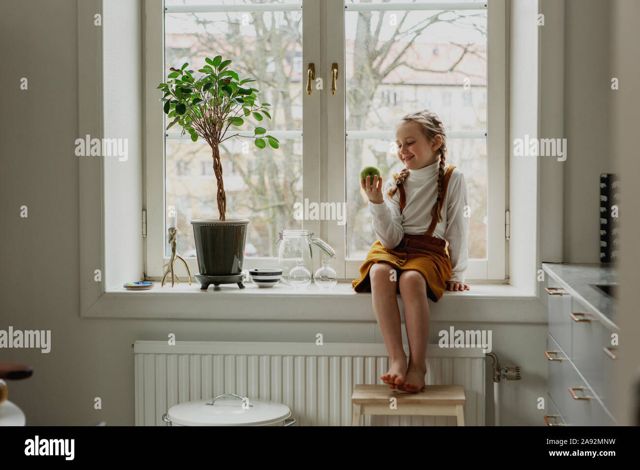 Lächelnde Mädchen sitzen auf Fensterbank Stockfoto
