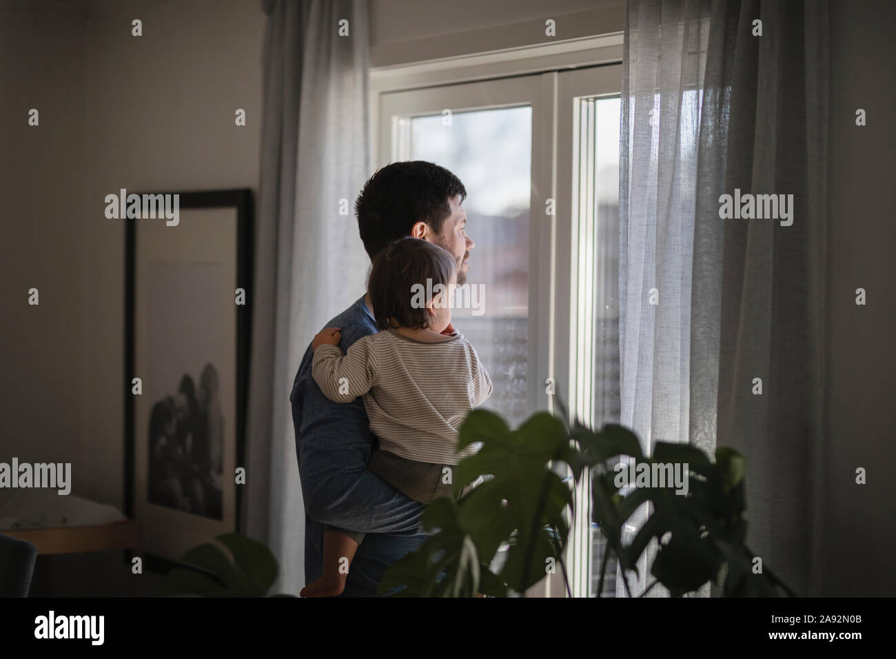 Vater mit Baby suchen durch das Fenster Stockfoto