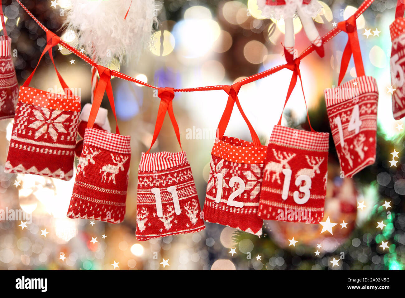 Kleine Beutel als Adventskalender mit Süßigkeiten Überraschungen hängen an einem Band gegen Leuchten verschwommenen Hintergrund Stockfoto