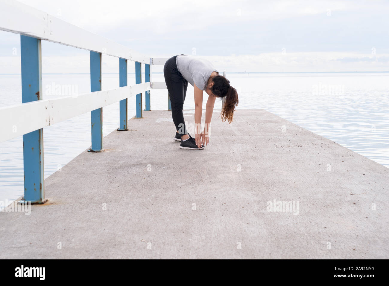 Frau stretching auf Jetty Stockfoto