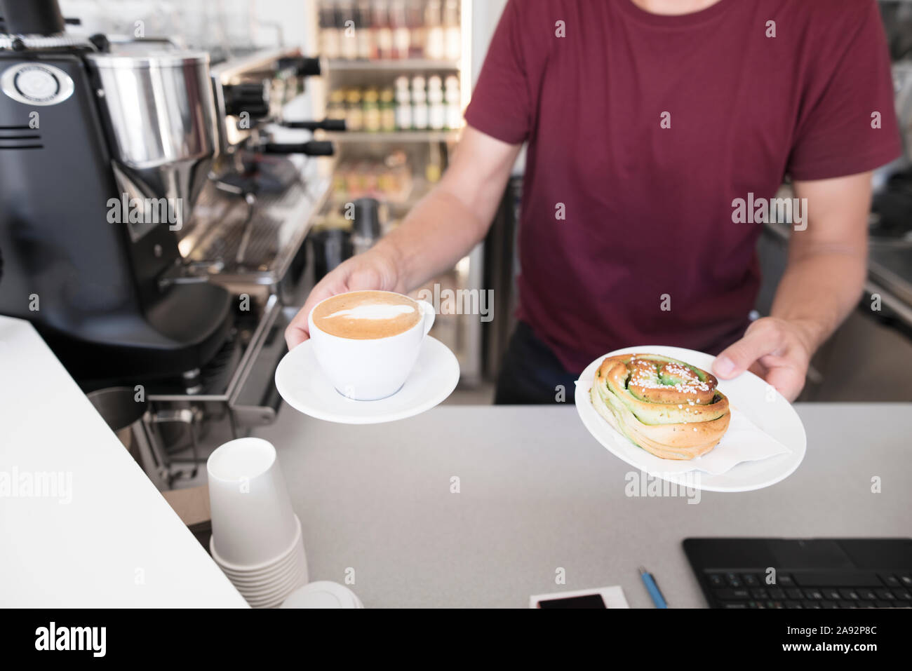 Barista holding Kaffee und Cinnamon Bun Stockfoto