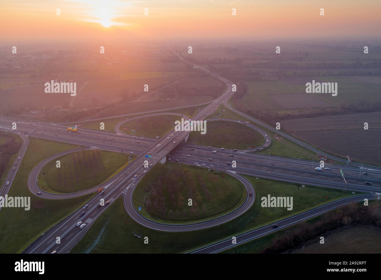 Kleeblatt interchange von oben gesehen. Luftaufnahme von Highway Kreuzung in der Poebene in der Nähe von Mailand bei Sonnenuntergang. Bird's Eye View. Stockfoto