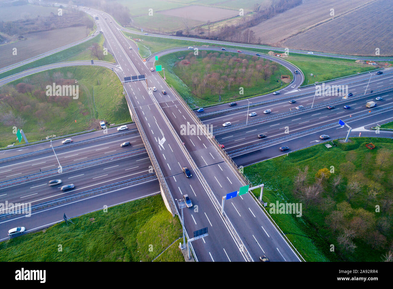 Kleeblatt interchange von oben gesehen. Luftaufnahme von Highway Kreuzung in der Poebene in der Nähe von Mailand bei Sonnenuntergang. Bird's Eye View. Stockfoto