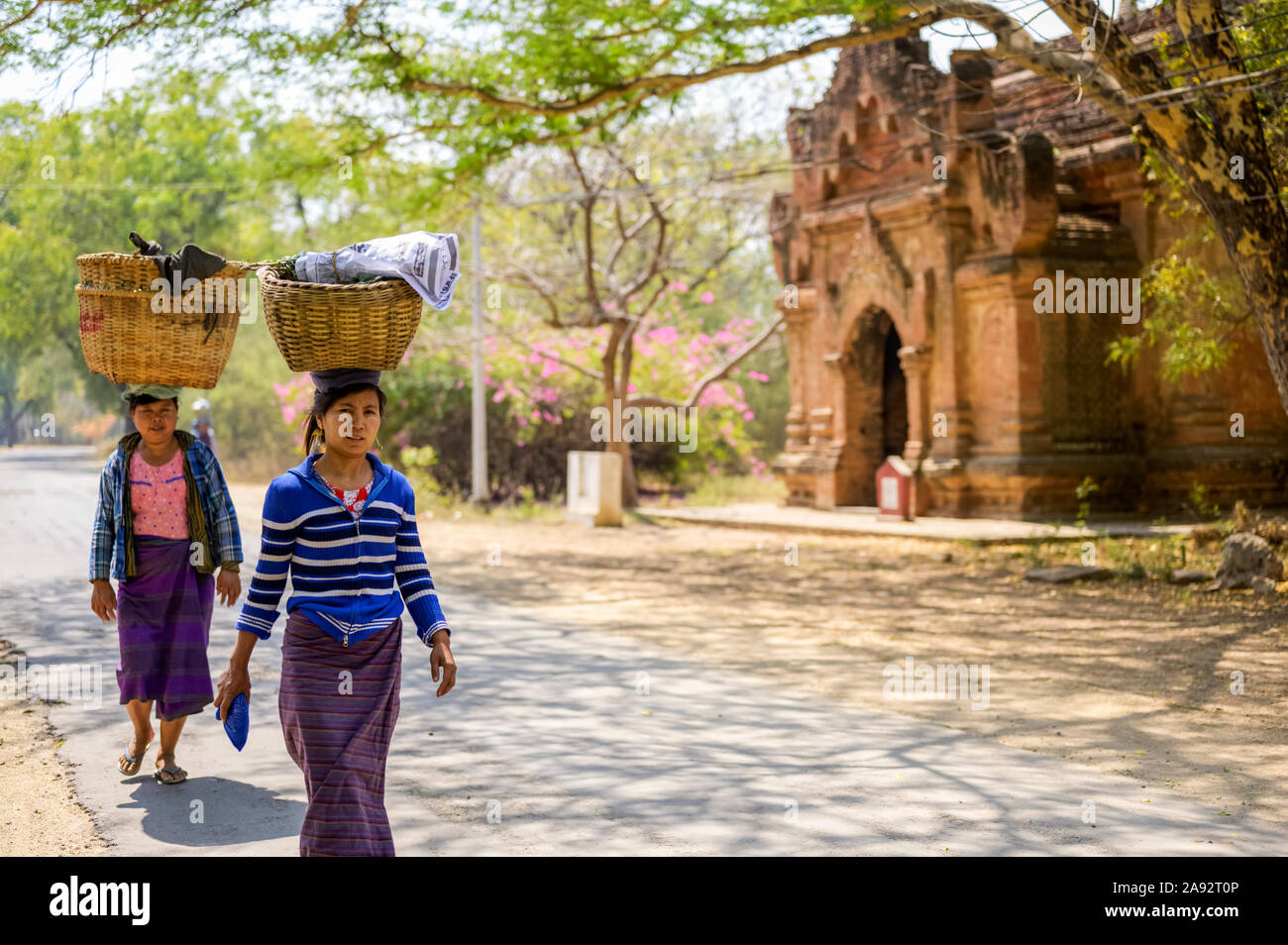 Frauen gehen mit Lasten auf dem Kopf; Bagan, Mandalay Region, Myanmar Stockfoto