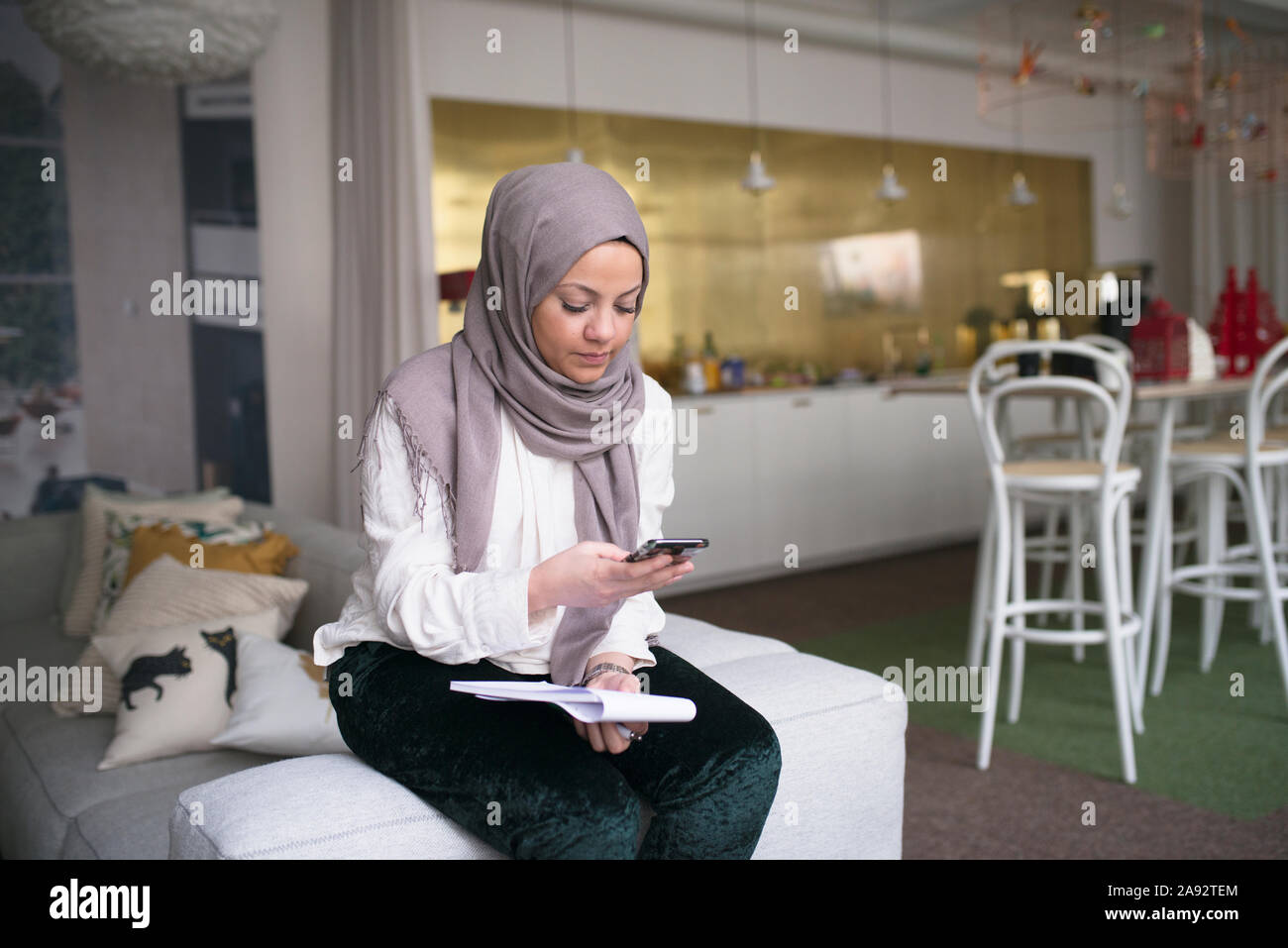 Junge Frau mit Smartphone im Büro Stockfoto