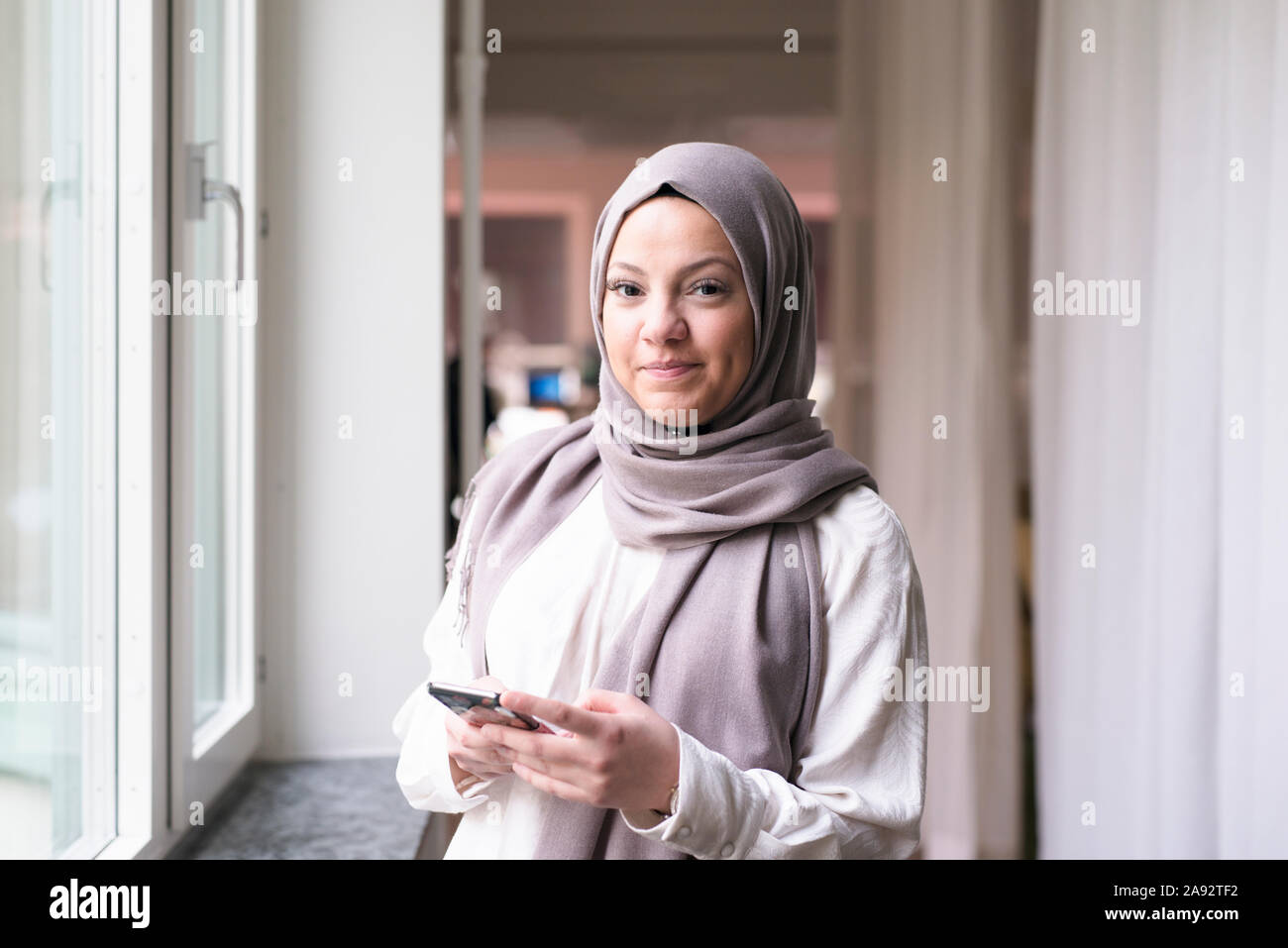 Junge Frau mit Smartphone im Büro Stockfoto