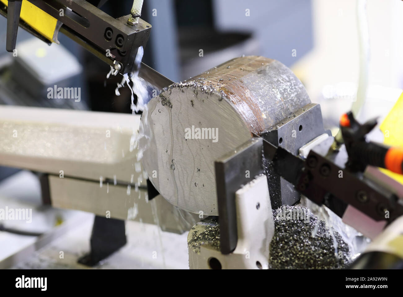 Automatische industrielle Bandsäge Zerspanung die Metallstange mit der Kühlflüssigkeit. Selektive konzentrieren. Stockfoto
