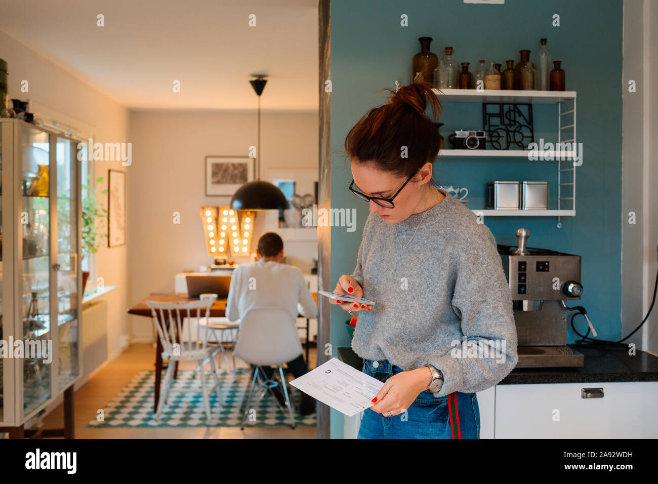 Junge Frau mit Smartphone in der Küche Stockfoto