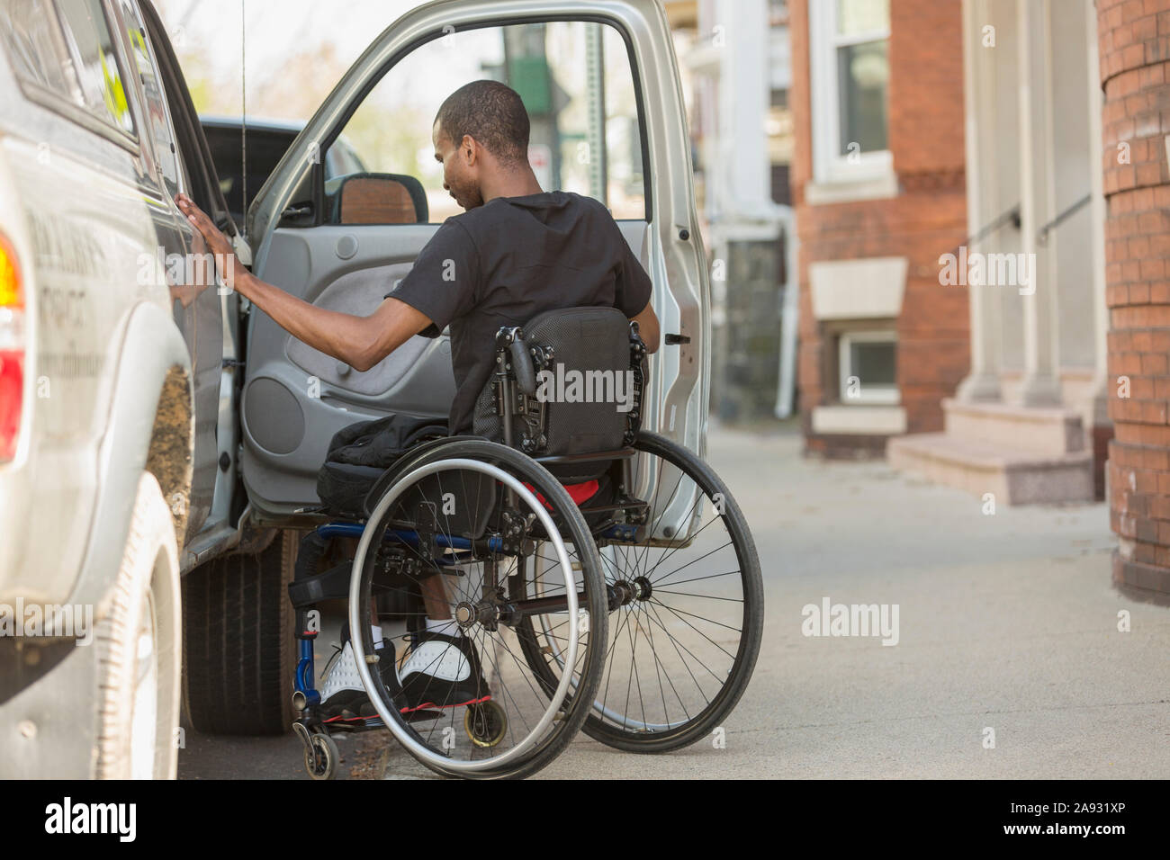 Mann in einem Rollstuhl, der eine Spinale Meningitis hatte, trat in seinen ein Barrierefreies Fahrzeug Stockfoto