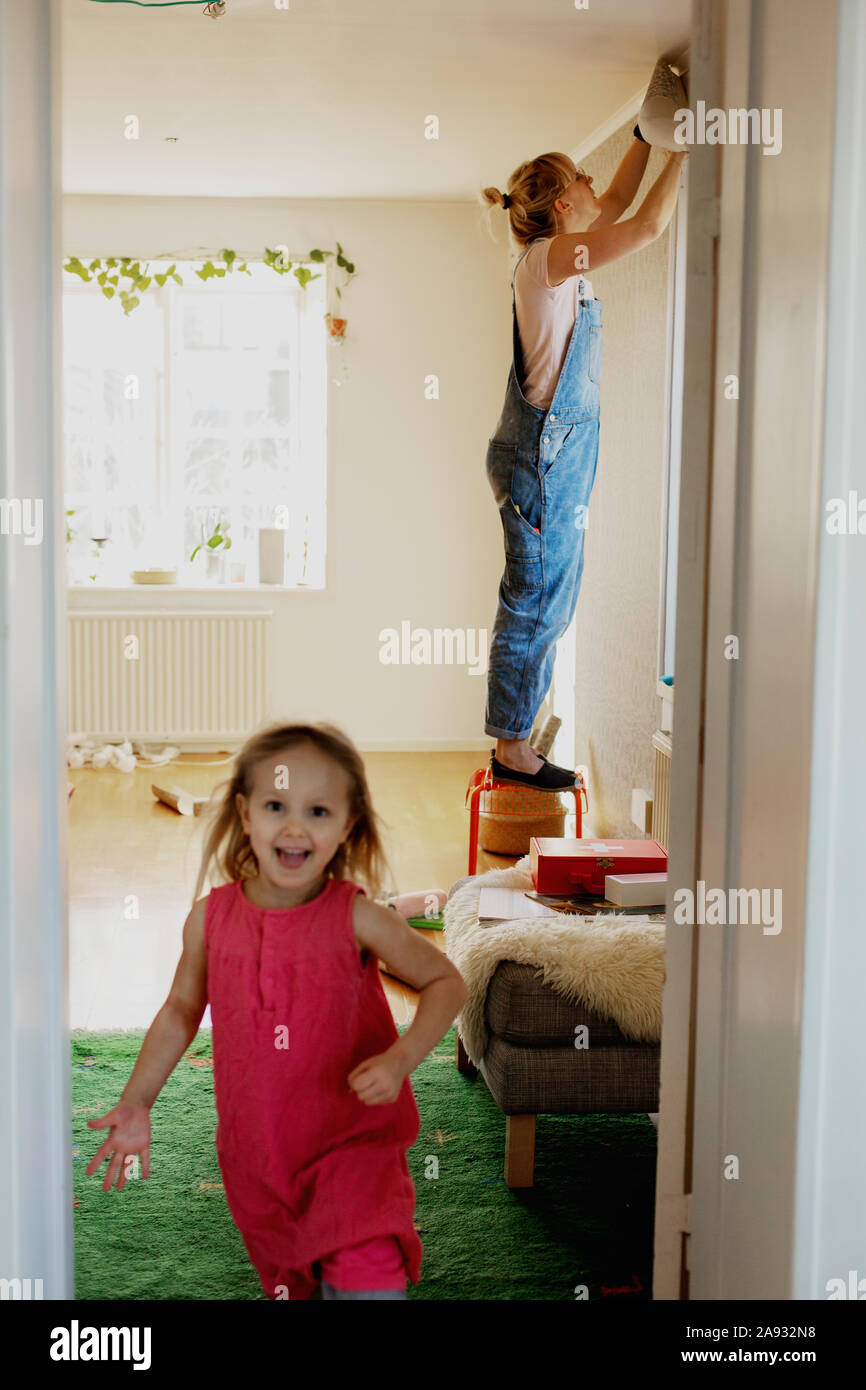 Frau kleben Tapeten an Wand, Mädchen im Vordergrund Stockfotografie - Alamy