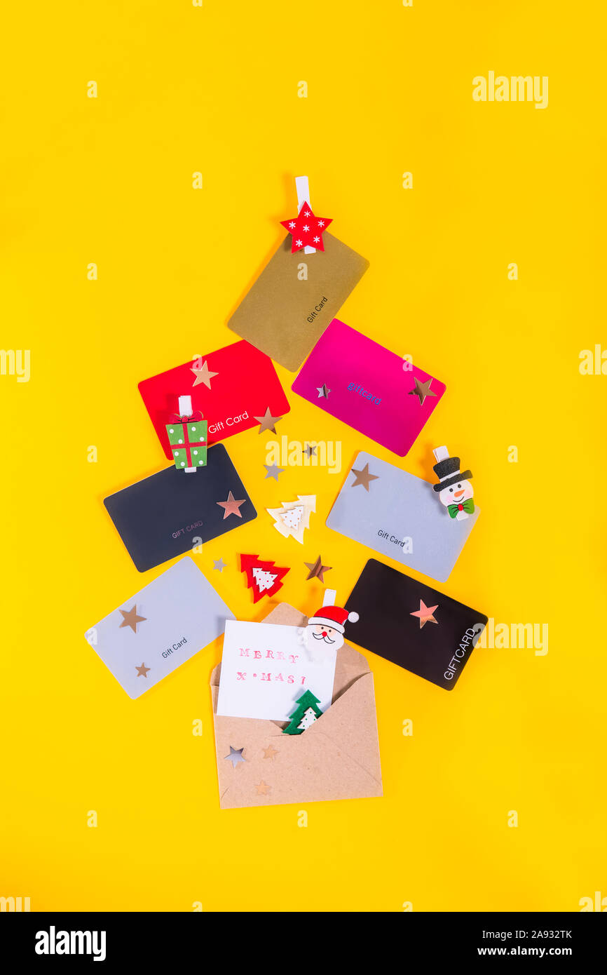 Bunte Store Karten, Dekor und Gruß Merry X-Mas Karte mit Umschlag in Form der Weihnachtsbaum auf gelben Hintergrund. Flatlay. Neues Jahr Stockfoto