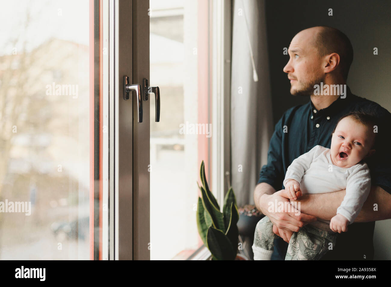 Vater mit Baby suchen durch das Fenster Stockfoto
