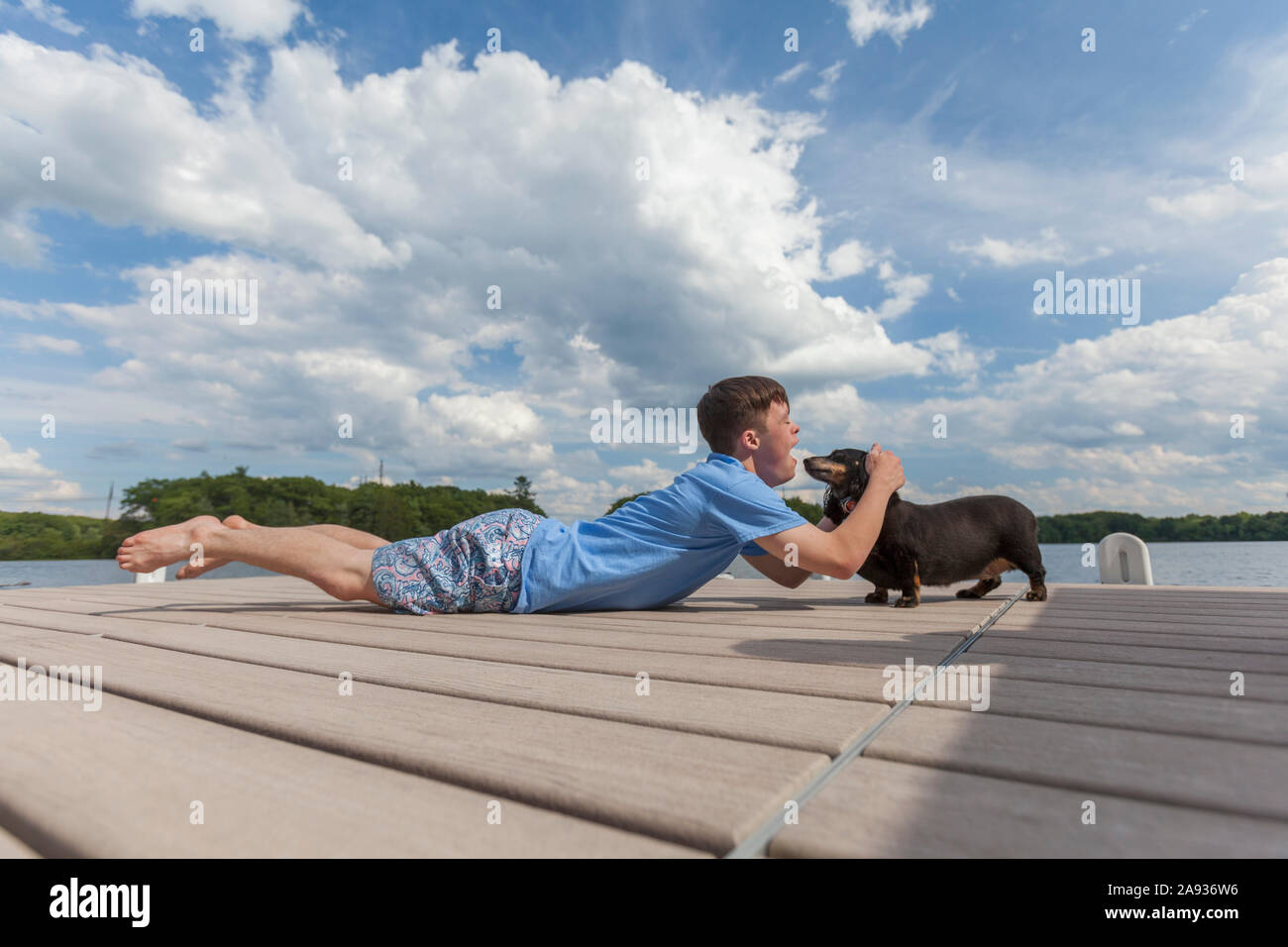 Junger Mann mit Down-Syndrom spielt mit einem Hund an Ein Dock Stockfoto