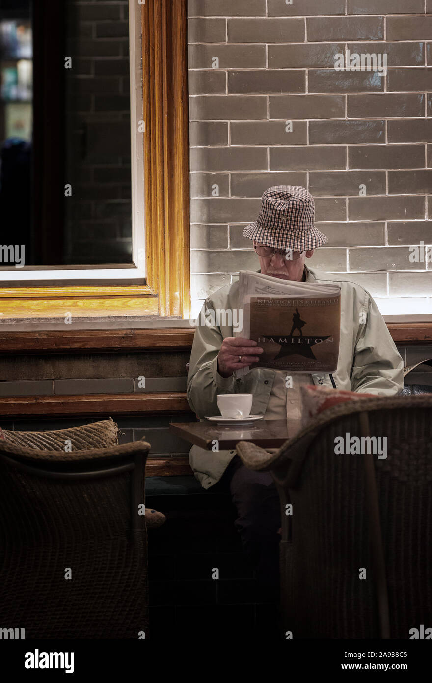 Mann liest Zeitung und Tee trinken im Café zu Barter Books, Alnwick, Northumberland, Großbritannien Stockfoto