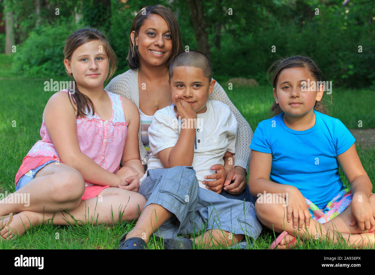 Hispanische Familie mit autistischen Jungen, die zusammen im Park sitzen Stockfoto