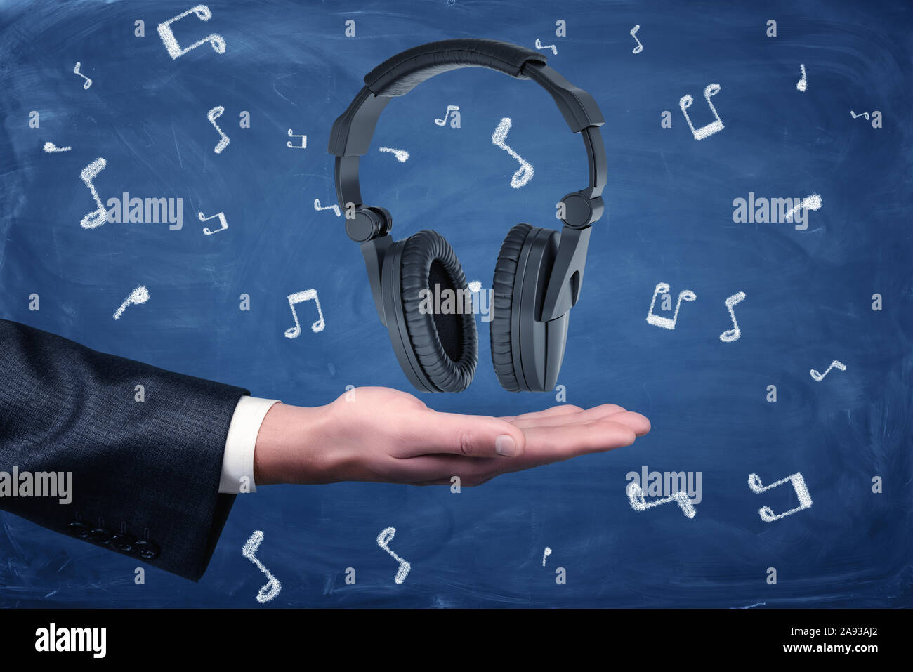 Männliche Hand schwarz Kopfhörer auf Blau Musik Zeichen Muster Hintergrund Stockfoto