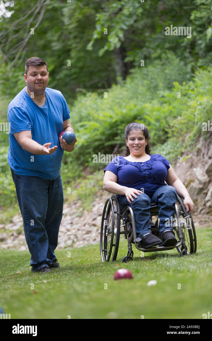 Frau mit Spina Bifida im Rollstuhl, die Bocce Ball spielt Mit ihrem Mann Stockfoto