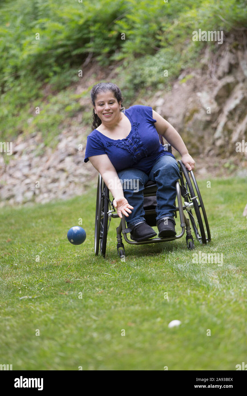 Frau mit Spina Bifida im Rollstuhl, die Bocce Ball spielt Stockfoto