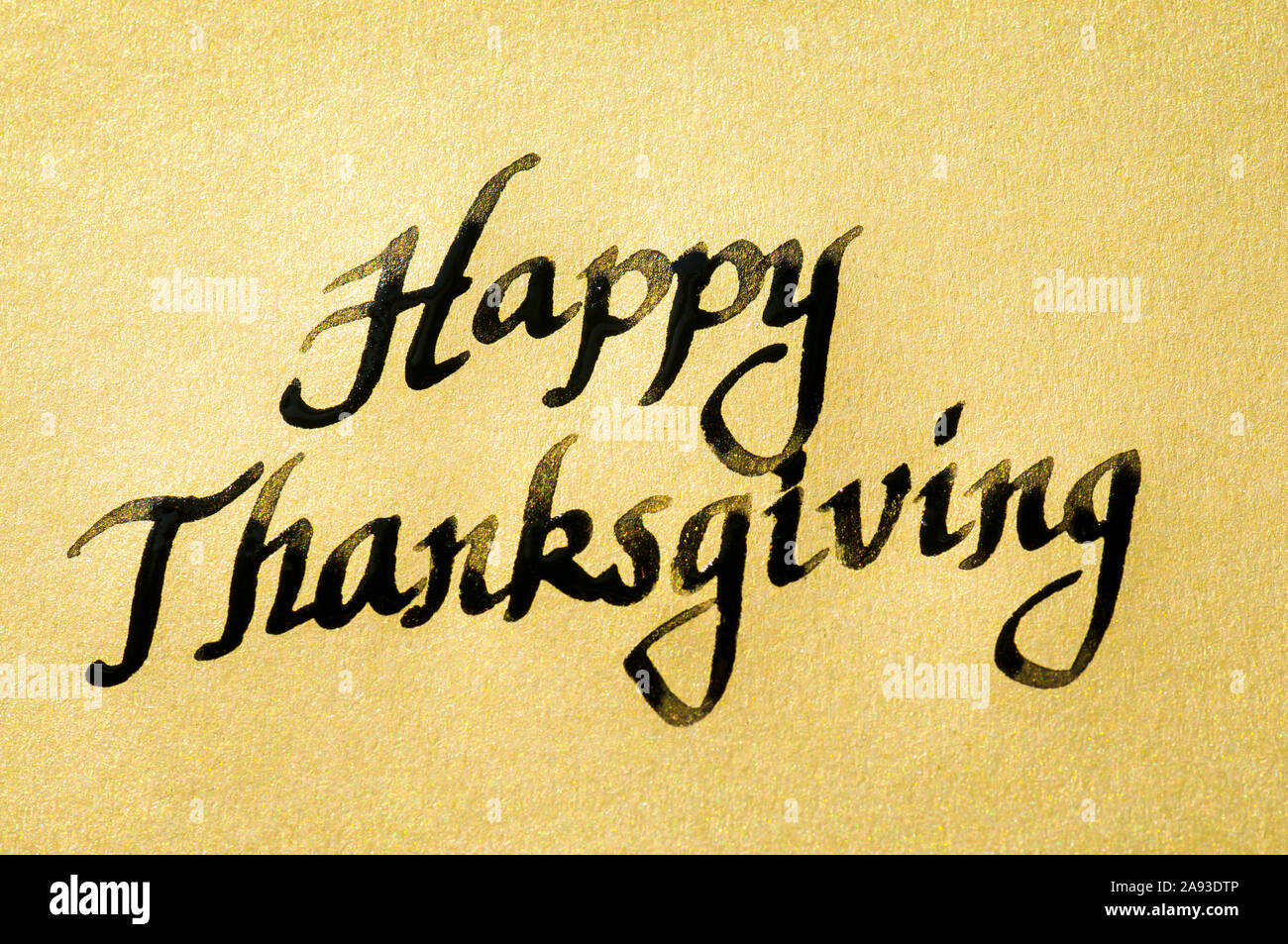 Happy Thanksgiving Nachricht handschriftlich in schwarzer Kalligraphie Skript auf strukturierte gold Papier Stockfoto
