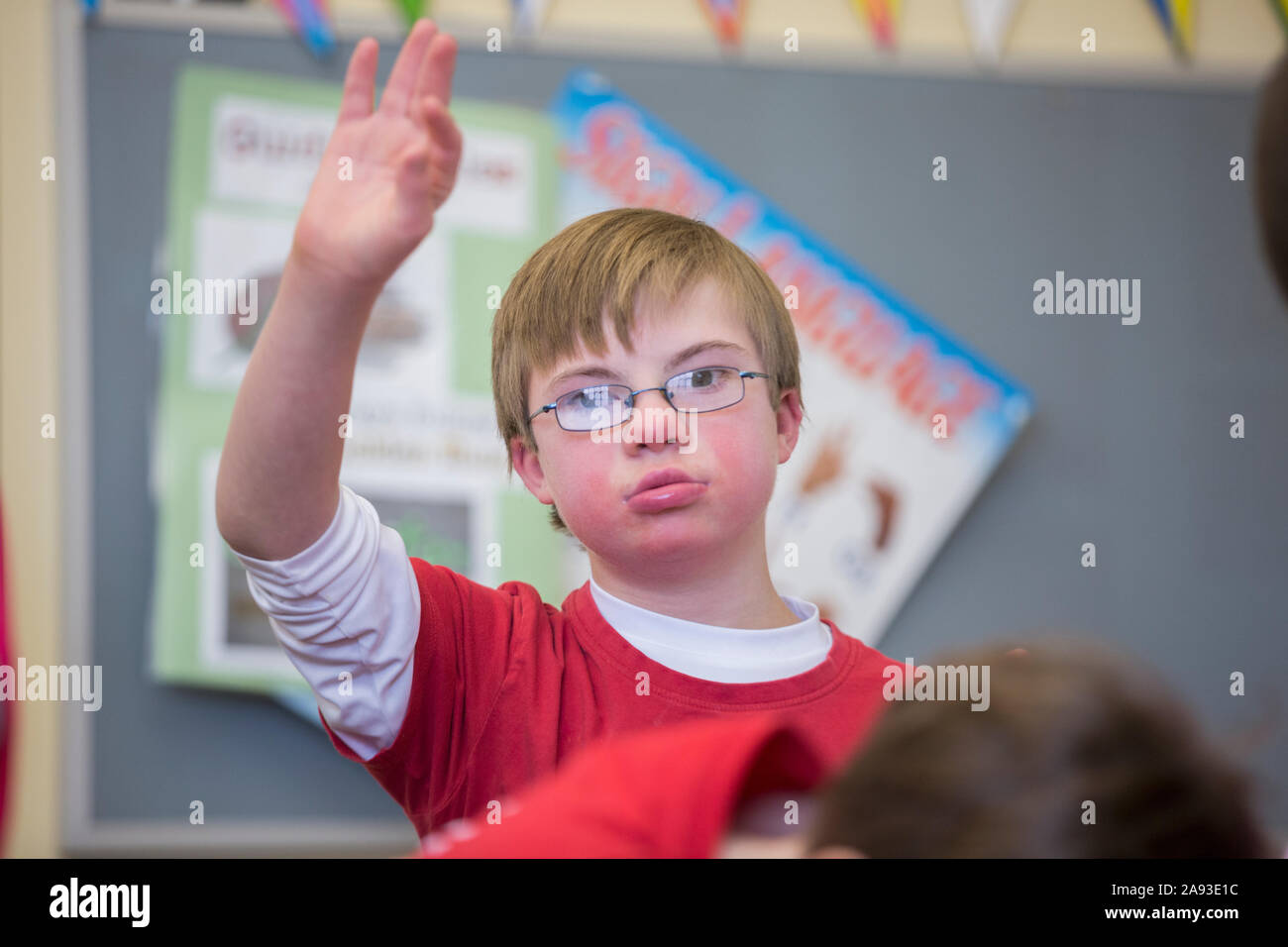 Junge mit Down-Syndrom Heben Hand in einer Schule Klassenzimmer Stockfoto