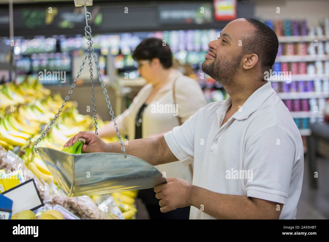 Mann mit Down-Syndrom wiegt Banane in einem Lebensmittelgeschäft Stockfoto